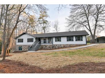 Charming home featuring stone accents, a welcoming front porch, and newly built stairs, surrounded by mature trees at 2923 Glenhaven Sw Ct, Conyers, GA 30094