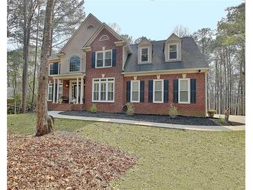 Charming two-story brick home with a manicured lawn and classic architectural details at 155 Woodcreek Ln, Fayetteville, GA 30215
