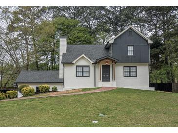 Charming home featuring white painted brick, dark trim, and a brick walkway leading to the front door at 2048 Kelvin Dr, Lawrenceville, GA 30043