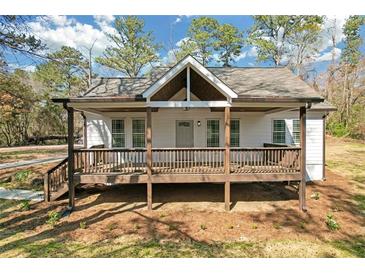 Charming home featuring a cozy front porch, white siding, and mature trees at 2095 Highway 20 Ne, Conyers, GA 30012