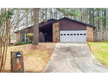 Charming home featuring a stone facade, two-car garage, and a long driveway leading up to the house at 3955 Chimney Ridge Ct, Ellenwood, GA 30294