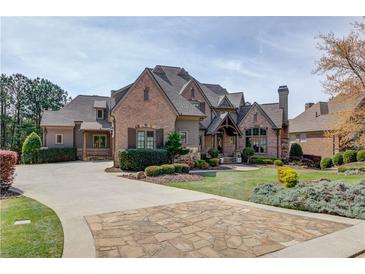 Stately brick home showcasing professionally landscaped grounds and an expansive driveway with stone accents at 5394 Brendlynn Dr, Suwanee, GA 30024