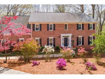 Charming two-story brick home featuring manicured landscaping with vibrant azaleas in a beautiful yard at 85 Cliffside Crossing, Atlanta, GA 30350