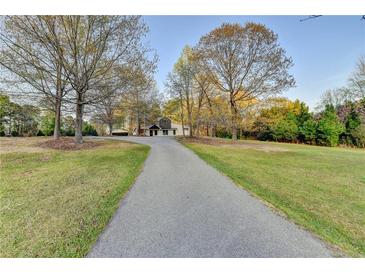 Long driveway leading up to a charming home surrounded by trees on a well-maintained lawn at 1880 Ridgedale Dr, Snellville, GA 30078