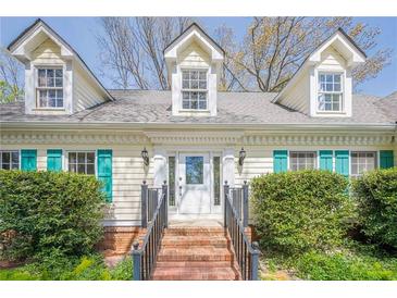 Charming home featuring dormer windows, teal shutters, and a welcoming brick front steps at 5215 Silver Creek Dr, Lilburn, GA 30047