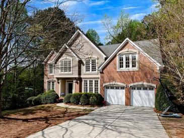 Charming two-story brick home with a well-manicured front yard and a spacious driveway leading to a two-car garage at 11770 Ashwick Pl, Johns Creek, GA 30005