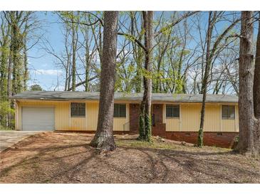 Charming single-story home with a light yellow facade and mature trees surrounding the property at 1360 Cypress Ridge Cir, Stone Mountain, GA 30083