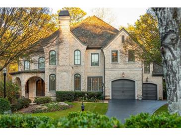 Charming two-story brick home with a manicured lawn, arched entryway, and attached two-car garage at 425 Prestwick Ct, Alpharetta, GA 30005