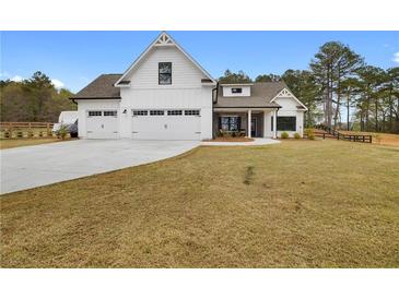 Beautiful white farmhouse-style home with a three-car garage and a large, sloping front lawn and mature landscaping at 4025 Bullock Bridge Rd, Loganville, GA 30052