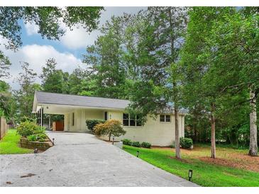 Charming single-story home with a light-colored brick exterior and a long driveway leading to a covered carport at 679 Forest Ridge Se Dr, Marietta, GA 30067