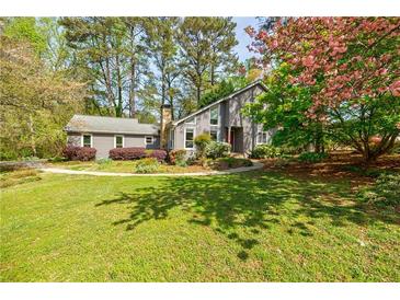 Charming home with a well-manicured lawn, stone chimney, and beautiful landscaping at 4183 Oak Crest Dr, Tucker, GA 30084