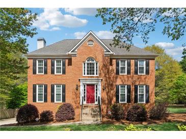 Traditional brick home with black shutters, a red front door, and a well-maintained landscaped lawn at 1075 Pebble Bend Dr, Grayson, GA 30017