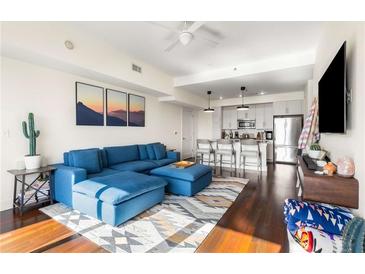 Open-concept living room flows to the kitchen, featuring a sectional sofa, modern art, and hardwood floors at 1100 Howell Mill Nw Rd # 711, Atlanta, GA 30318