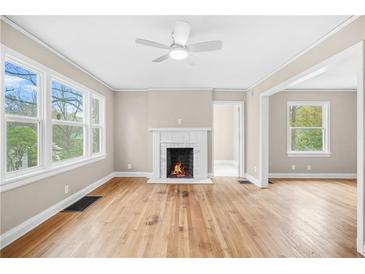 Bright living room with fireplace, ceiling fan, and large windows overlooking the surrounding greenery at 1910 Thompson Ave, East Point, GA 30344