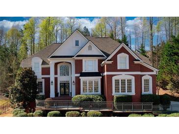 Stately brick home with manicured landscaping, large windows, and an elegant entrance framed by white pillars at 4777 Ardmore Ln, Hoschton, GA 30548