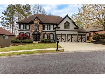 Beautiful two-story home with stone and stucco facade, manicured lawn, and three-car garage at 622 Goldpoint Trce, Woodstock, GA 30189