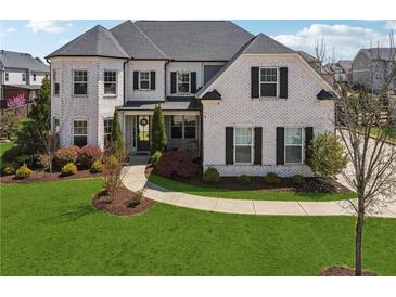 Beautiful two-story white brick home with black shutters and a well-manicured lawn at 214 Leland Way, Woodstock, GA 30188