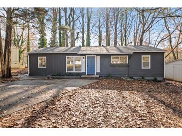 Charming exterior featuring a grey painted home, a blue door, and a leaf-covered front yard and drive at 799 Kennesaw Dr, Forest Park, GA 30297
