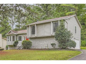 Charming home featuring stone accents, a red front door, a well-maintained lawn and mature trees at 1945 Chateau Ln, Lithia Springs, GA 30122