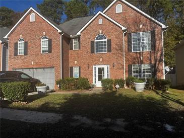 Charming two-story brick home with an attached garage and manicured landscaping creating an inviting curb appeal at 5009 Duval Point Sw Way, Snellville, GA 30039