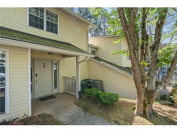 Inviting townhouse featuring a charming front porch and neutral siding complemented by lush greenery and mature trees at 6810-G Glenridge Dr, Atlanta, GA 30328
