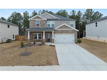 Charming two-story home with stone accents, an attached garage, and a long driveway with neat landscaping at 4171 Dean Grove Way, Loganville, GA 30052