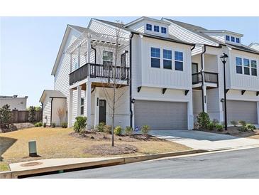 Charming two-story townhome with a gray garage door, balcony, and manicured lawn at 1433 Halpern Ln, Kennesaw, GA 30144