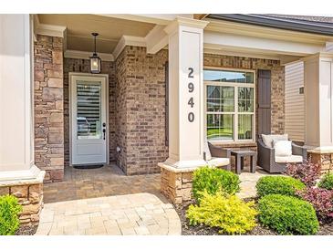 Inviting covered front porch with brick accents, stylish seating, and well-manicured landscaping at 2940 W Village Dr # 60, Suwanee, GA 30024