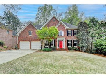 Charming two-story brick home with a manicured lawn, complemented by a vibrant red front door and a two-car garage at 10460 Cranchester Way, Alpharetta, GA 30022