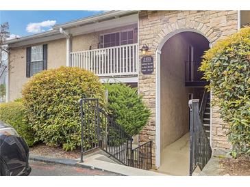 View of exterior featuring stone accents, stairwell to units, and mature landscaping around the building at 3155 Seven Pines Ct # 303, Atlanta, GA 30339