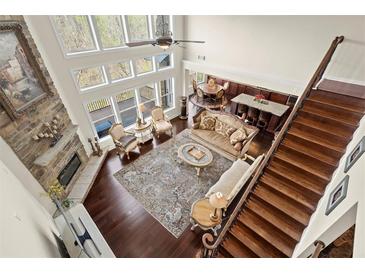 Open-concept living room with a stone fireplace, floor-to-ceiling windows, and hardwood floors offers a cozy and bright space at 2875 Waterstone Dr, Cumming, GA 30041