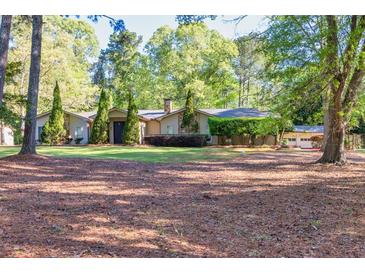 Ranch-style home featuring a manicured front lawn with mature trees and a charming front entrance at 2701 East Mill Sw Way, Conyers, GA 30094