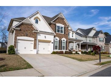 Charming two-story home boasts a stone and white painted brick facade, and a spacious two-car garage at 4125 Hidden River Dr, Cumming, GA 30028