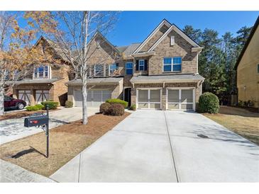 Beautiful brick townhome with a two-car garage and well-maintained landscaping and a long driveway at 6160 Shiloh Woods Dr, Cumming, GA 30040