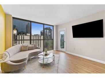 Bright living room features a curved sofa, city views from large windows, and modern decor at 1280 W Peachtree Nw St # 1712, Atlanta, GA 30309