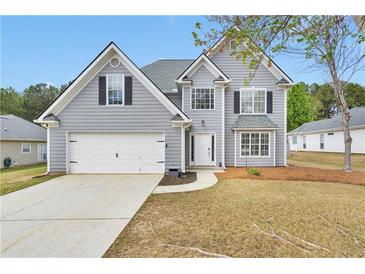 Charming two-story home with gray siding, attached garage, and well-manicured front yard at 2061 Emerald Dr, Loganville, GA 30052