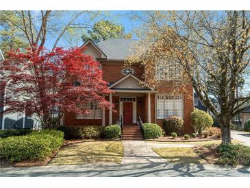 Charming brick home featuring a manicured lawn, mature trees, and classic architectural details, creating inviting curb appeal at 4045 Stephens Mill Ne Run, Atlanta, GA 30342