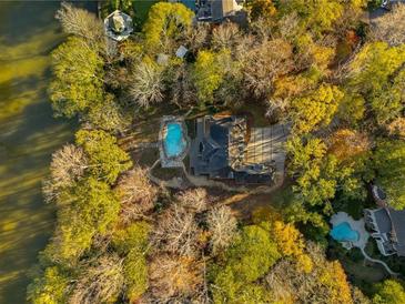Breathtaking aerial view of estate home with sparkling pool surrounded by colorful fall foliage near the water at 1840 Brandon Hall Dr, Atlanta, GA 30350