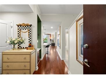 Bright condo hallway with hardwood floors leading to the open kitchen area and featuring a decorative mirror and chest at 3300 Windy Ridge Se Pkwy # 612, Atlanta, GA 30339
