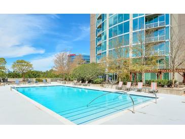 A beautiful in-ground swimming pool with ample lounge seating surrounded by trees and a view of a high rise building at 3300 Windy Ridge Se Pkwy # 612, Atlanta, GA 30339