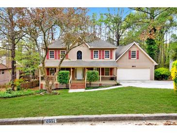 Charming two-story home featuring a well-manicured lawn, red shutters, and a two-car garage at 2611 Rock Point Ln, Snellville, GA 30039