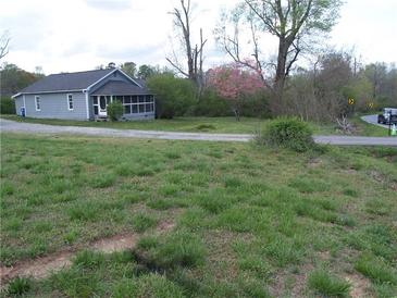 Charming home with a screened-in porch and gravel driveway surrounded by a lush green lawn and mature trees at 3915 Dahlonega Hwy, Cumming, GA 30028