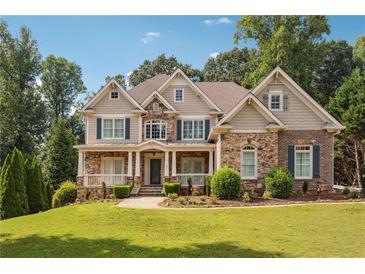 Stunning two-story home featuring a stone and brick facade with a welcoming front porch and beautifully landscaped yard at 3275 Aldrich Dr, Cumming, GA 30040