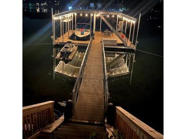 Picturesque dock featuring a boat and jet ski on a peaceful lake at night at 6160 Lake Lanier Heights Rd, Buford, GA 30518