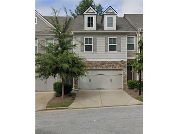 Charming two-story townhome featuring a two-car garage, stone accents, and well-maintained landscaping at 1563 Butternut Cv, Stone Mountain, GA 30083