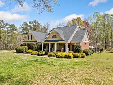 Charming brick home featuring a well-manicured lawn, lush landscaping, and inviting front porch with rocking chairs at 5660 Trout Creek Dr, Douglasville, GA 30135