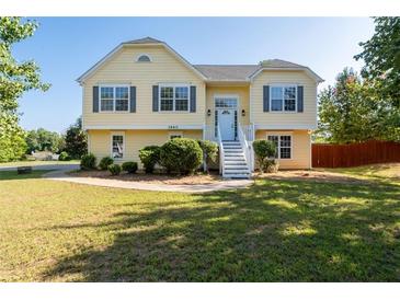 Charming two-story yellow home with landscaped front yard, grey shutters and white stairs at 3540 Owl Brow Ct, Cumming, GA 30028