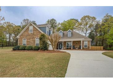 Charming stone and siding home with a well-manicured lawn and a long concrete driveway at 135 Clear Spring Lane, Oxford, GA 30054