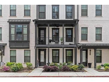 Charming townhome with a balcony, white brick, black trim, and well manicured landscaping at 4651 Eddibunn Se Dr, Smyrna, GA 30080
