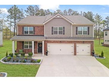 Charming two-story home with a landscaped yard and two-car garage and mixed brick and siding facade at 8033 Louis Dr, Locust Grove, GA 30248